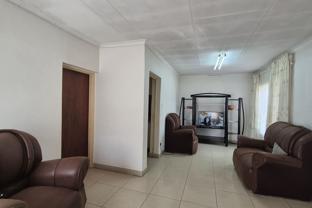 A living room featuring tiled flooring and coved ceilings, requiring cosmetic updates to address ceiling staining and improve overall aesthetic appeal.
