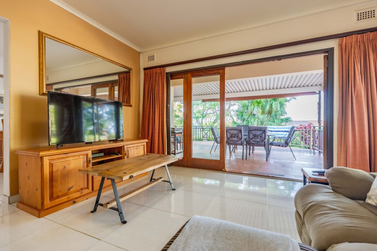 Living room featuring large format floor tiles and wide sliding glass doors providing seamless access to the covered outdoor patio area.