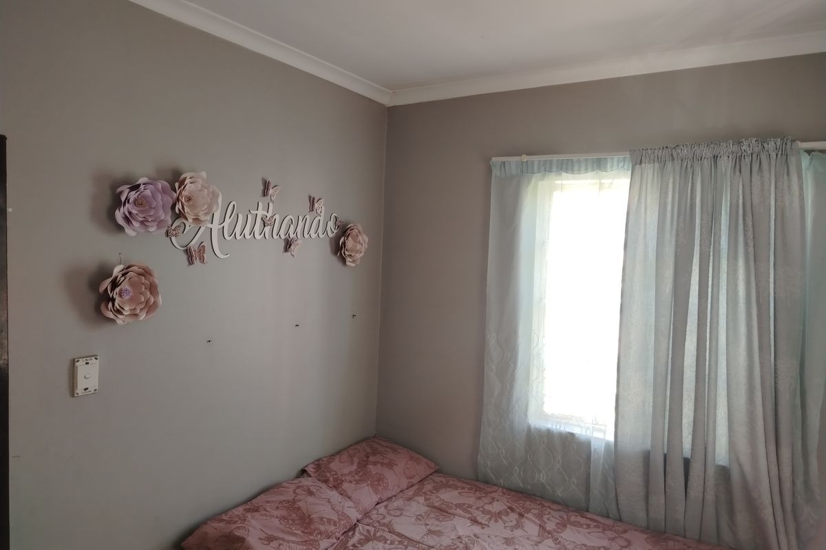 A bedroom featuring neutral wall paint, a window with curtain tracks, and standard electrical outlets.