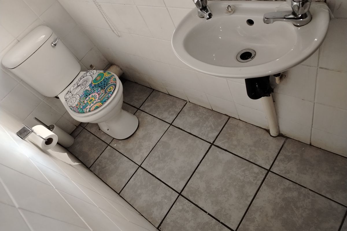 A compact guest bathroom featuring a standard toilet and wall-mounted basin with tiled walls and flooring.