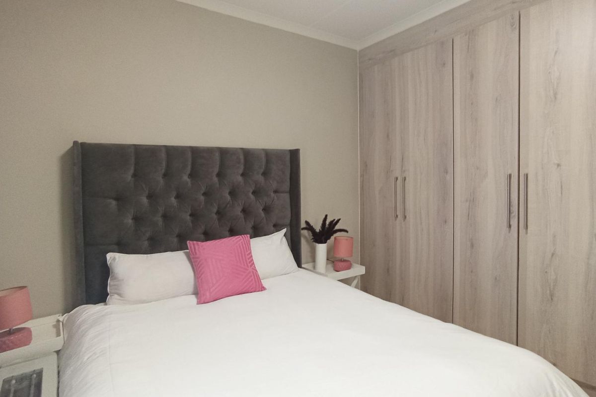 A well-maintained bedroom featuring neutral walls and extensive built-in wooden cupboards providing ample storage space.