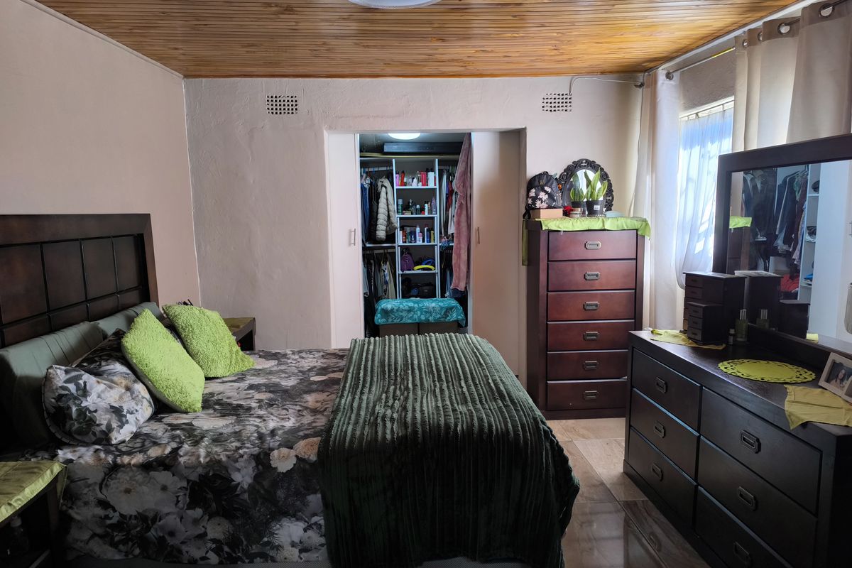 A bedroom featuring a timber-paneled ceiling, tiled flooring, and a built-in wardrobe with open shelving.