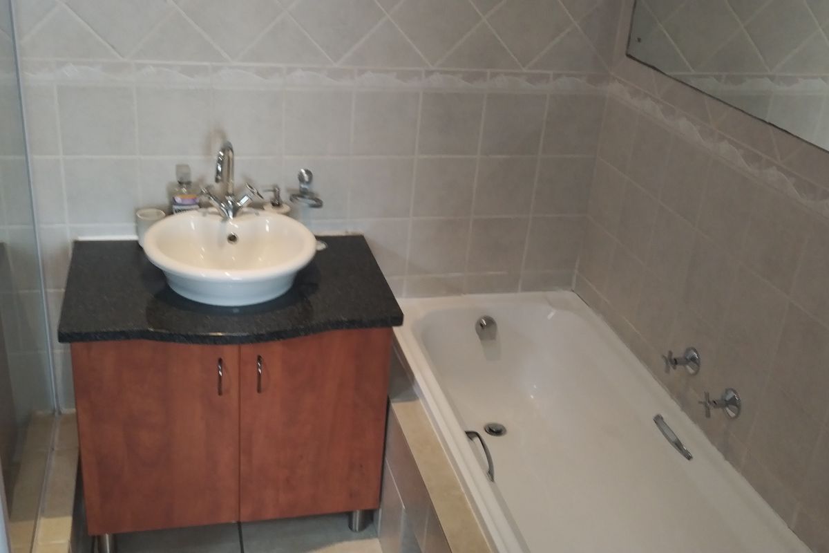 A functional bathroom featuring a vanity with a vessel sink, a built-in bathtub, and a separate shower enclosure with tiled walls.