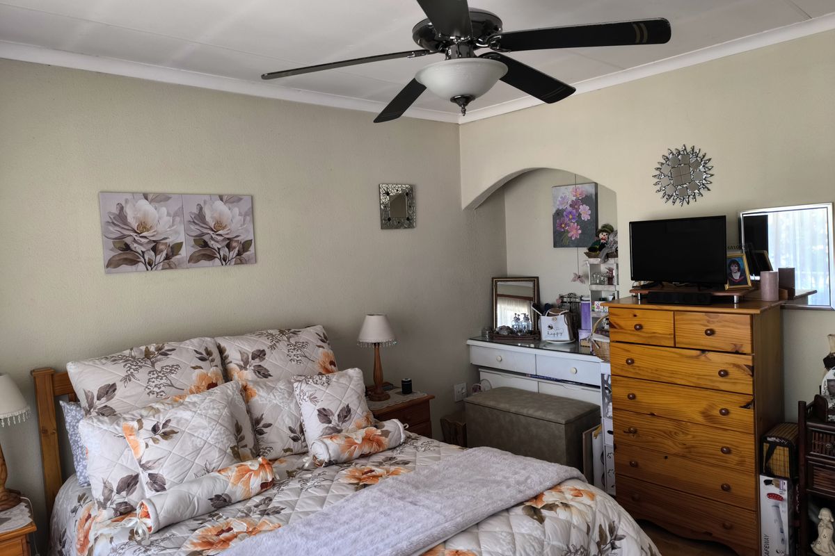 A cozy bedroom featuring a ceiling fan, coved ceilings, and a decorative archway leading to a vanity area.