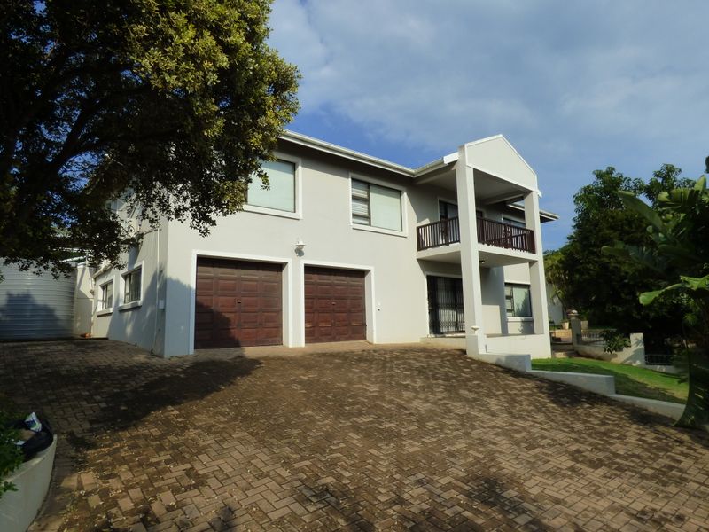 A double-storey residential property featuring a paved driveway, double garage, and an upper-level balcony with a neutral exterior finish.