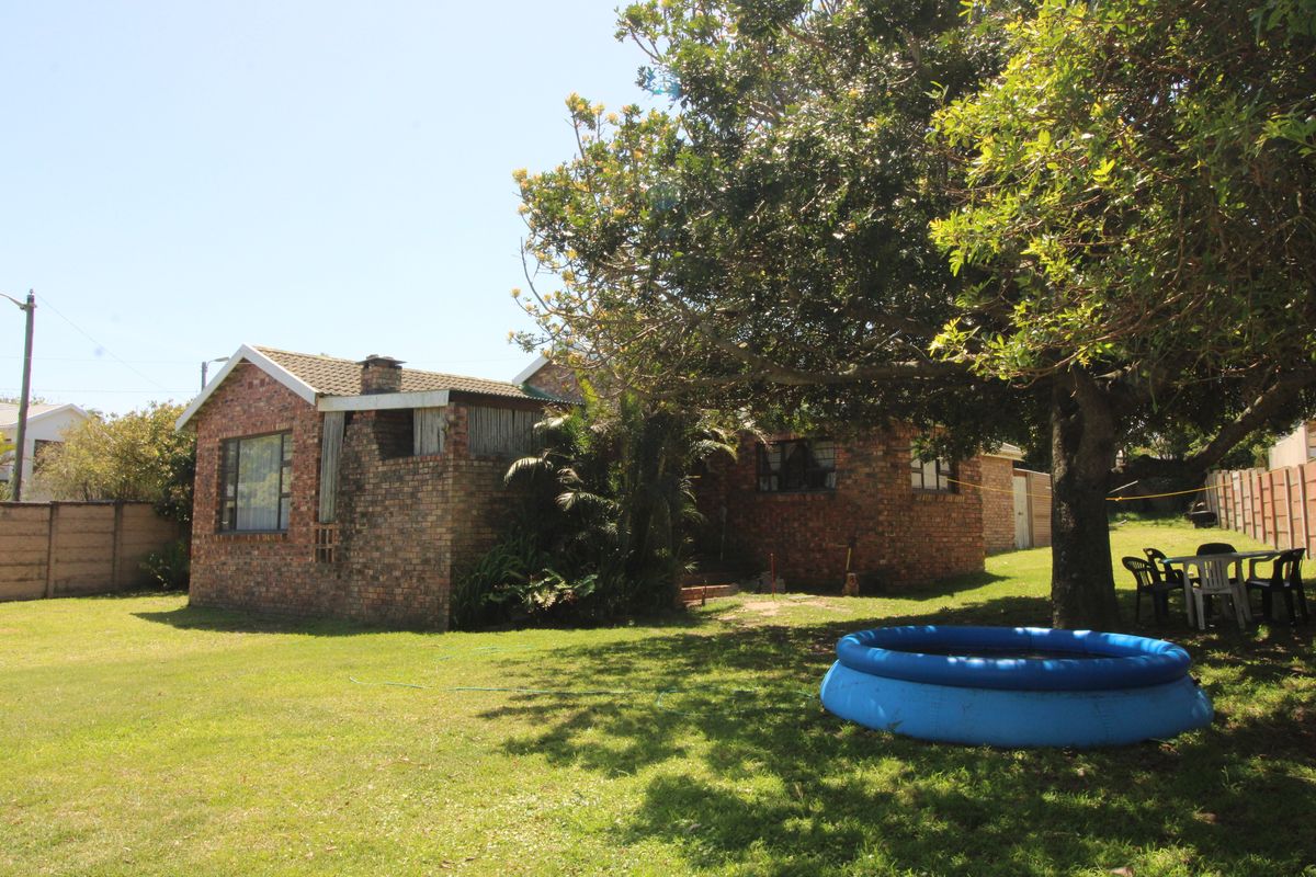 Rear view of a face brick house featuring a tiled roof, chimney, and a spacious garden area with mature trees.