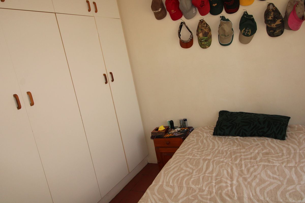 A bedroom featuring built-in cupboards with white cabinetry and tiled flooring.