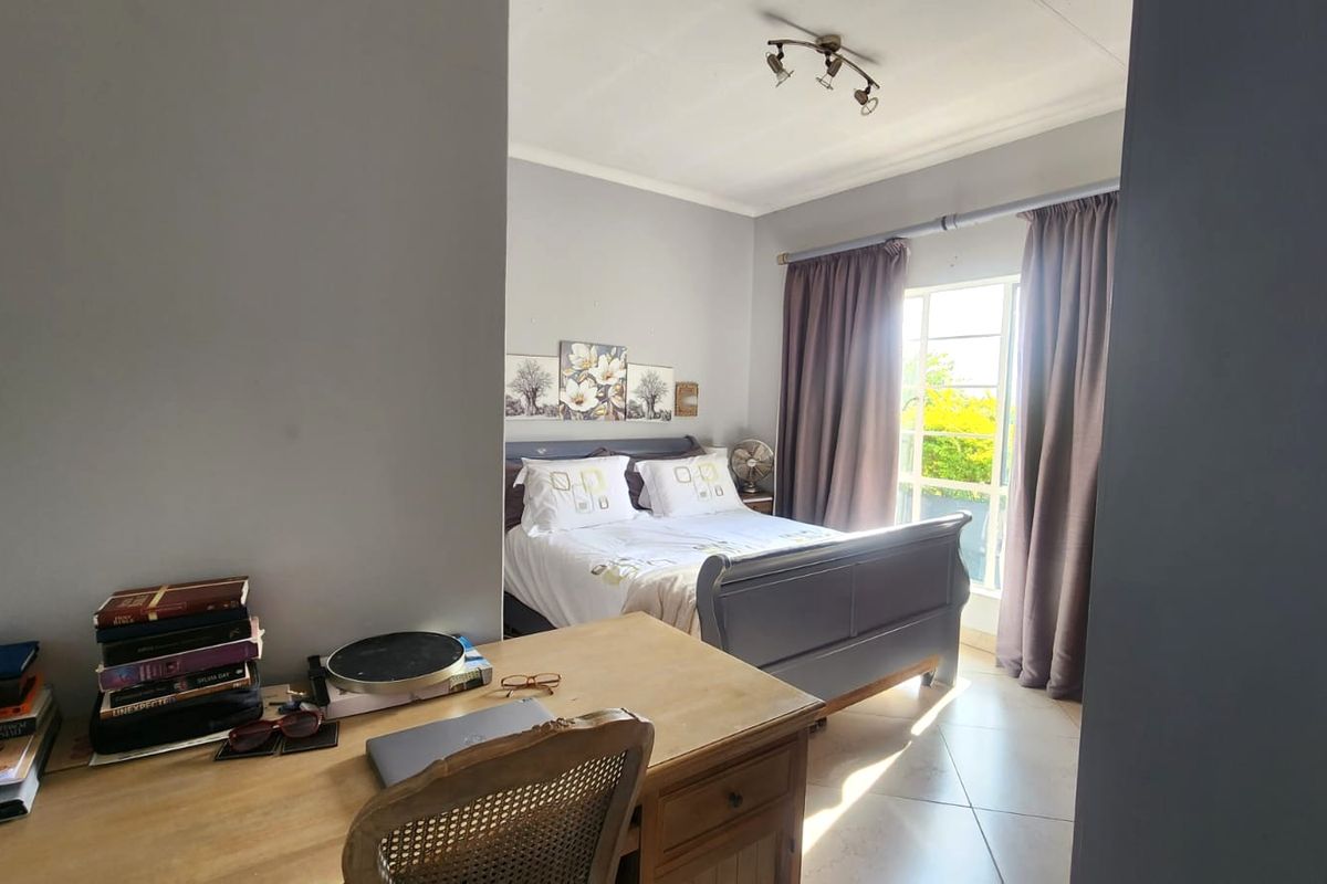 A bedroom featuring tiled flooring, neutral wall tones, and natural light through a window with curtain rails.