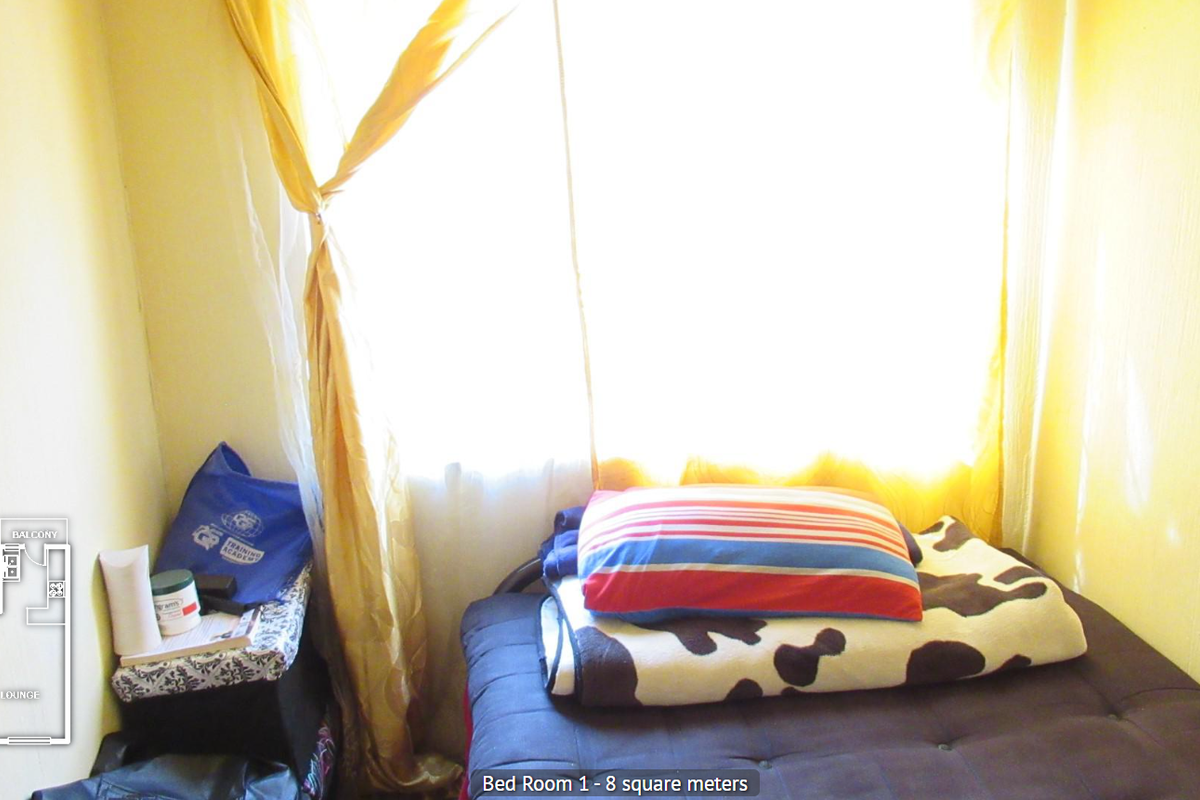 A small bedroom featuring a window with curtains and a floor plan overlay in the corner.