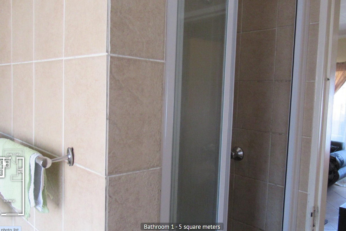 A functional bathroom featuring a shower enclosure with tiled walls and a wall-mounted towel rail.