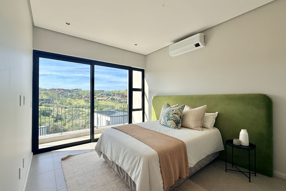 Modern bedroom featuring large sliding glass doors with scenic views, tiled flooring, recessed lighting, and a wall-mounted air conditioning unit.