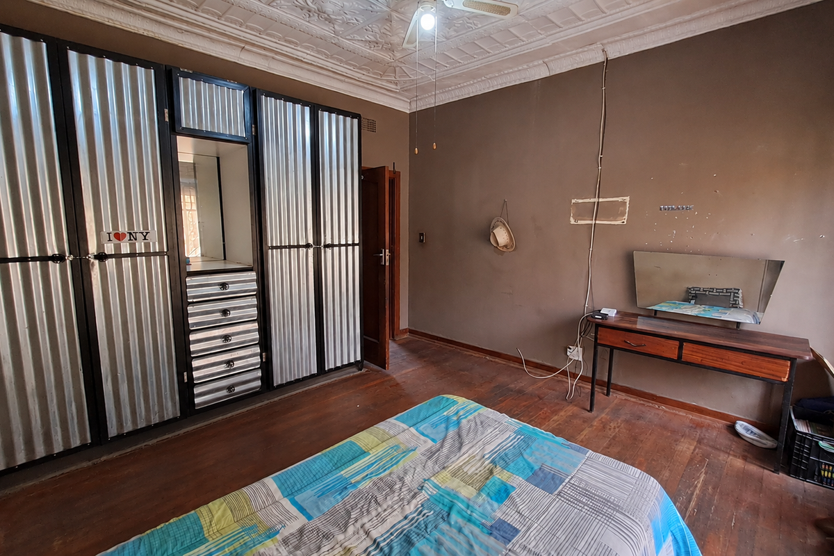 Bedroom featuring original ornate ceiling details, timber flooring, and a large industrial-style built-in wardrobe with corrugated metal finish.