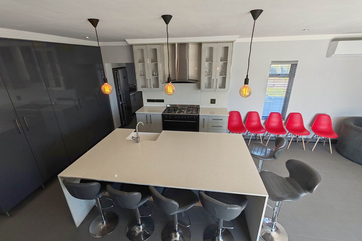 Modern kitchen featuring a large central island with quartz countertops, integrated cabinetry, gas stove, and extractor fan, complemented by contemporary pendant lighting.