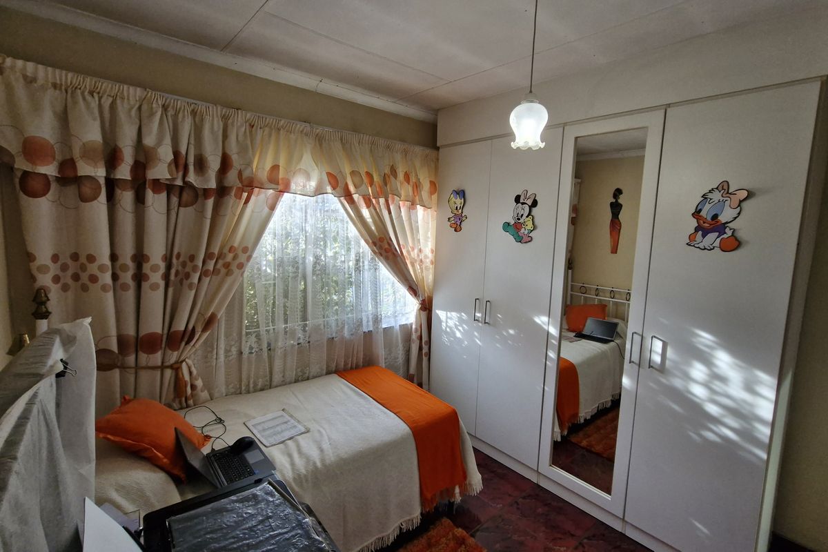 A functional bedroom featuring a built-in wardrobe with a mirrored panel, providing ample storage space and natural light through the window.