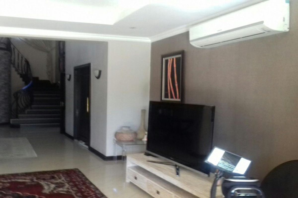 A living room featuring tiled flooring, a recessed ceiling, and a wall-mounted air conditioning unit, with an open view towards the staircase.
