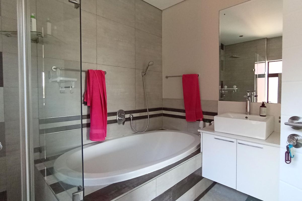 Modern bathroom featuring a built-in bathtub, glass-enclosed shower, vanity with vessel sink, and contemporary tiled finishes.