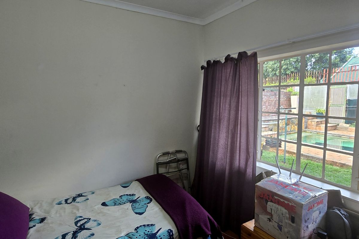 A bedroom featuring a large window with views of the garden and pool area, providing natural light.