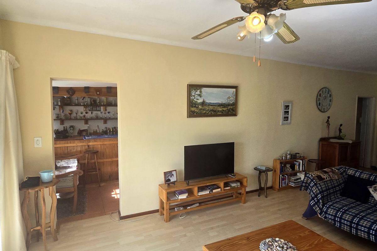 A spacious living room featuring laminate flooring, a ceiling fan, and a sliding glass door providing access to the exterior.