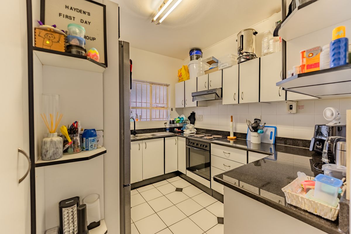 A functional kitchen featuring white cabinetry, dark granite countertops, a built-in oven with extractor fan, and tiled flooring.