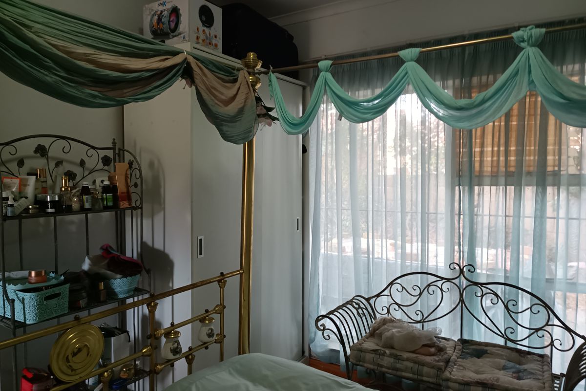 A bedroom featuring a built-in wardrobe with sliding doors and natural light filtering through window treatments.
