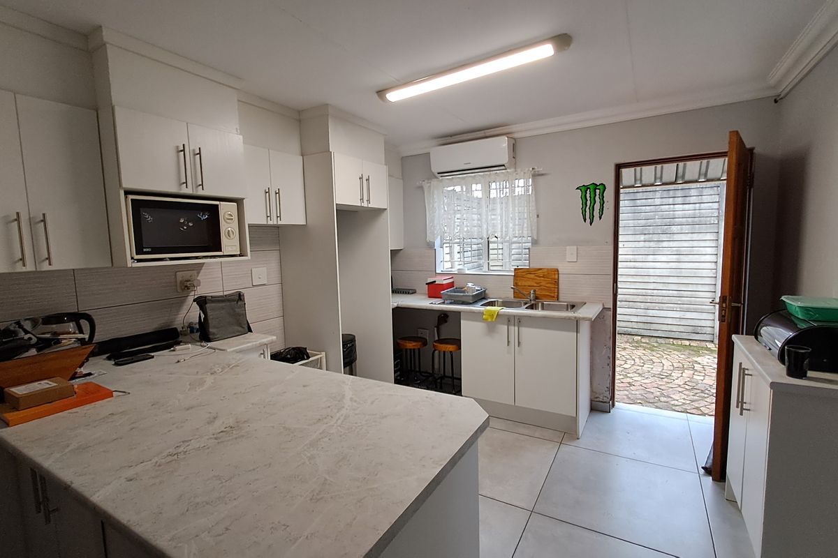 Functional kitchen featuring white cabinetry, stone-look countertops, tiled flooring, and direct access to an outdoor area.