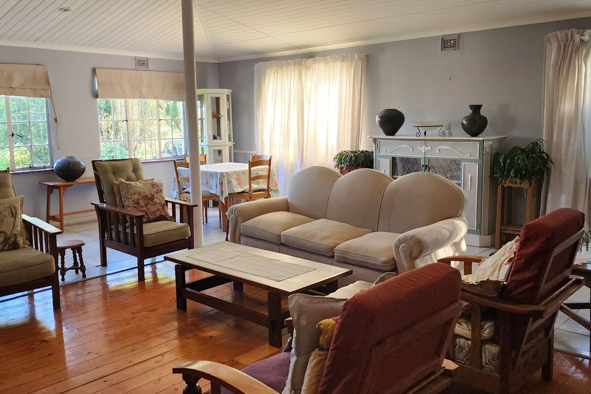 Spacious living area featuring warm timber flooring, exposed beam ceilings, and large windows that provide ample natural light.