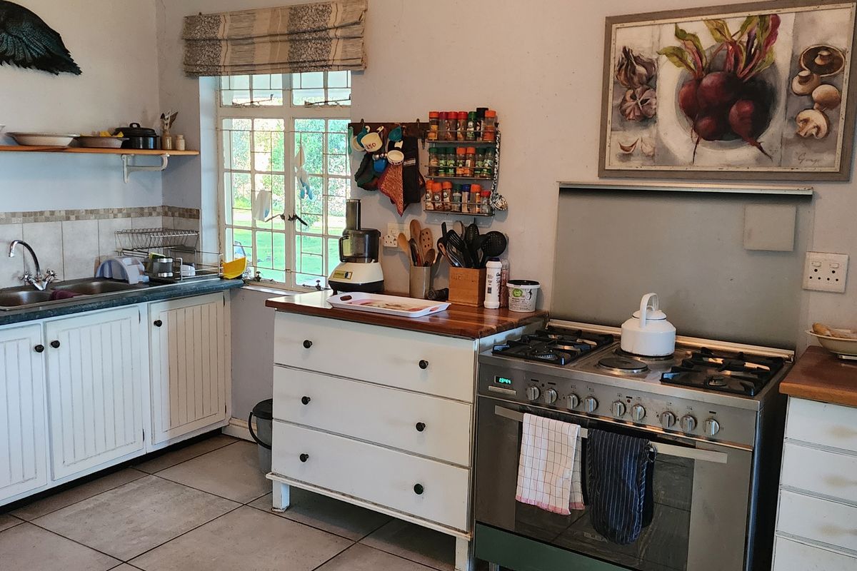 A functional kitchen featuring white cabinetry, wooden countertops, a gas stove with oven, and a double basin sink with tiled backsplash.