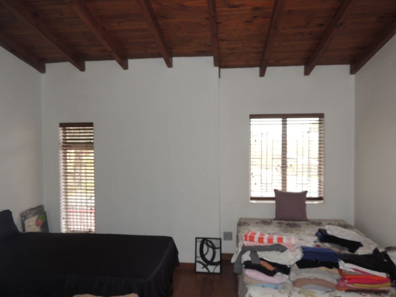 Bedroom featuring an exposed timber beam ceiling, timber blinds, and security bars on the windows.