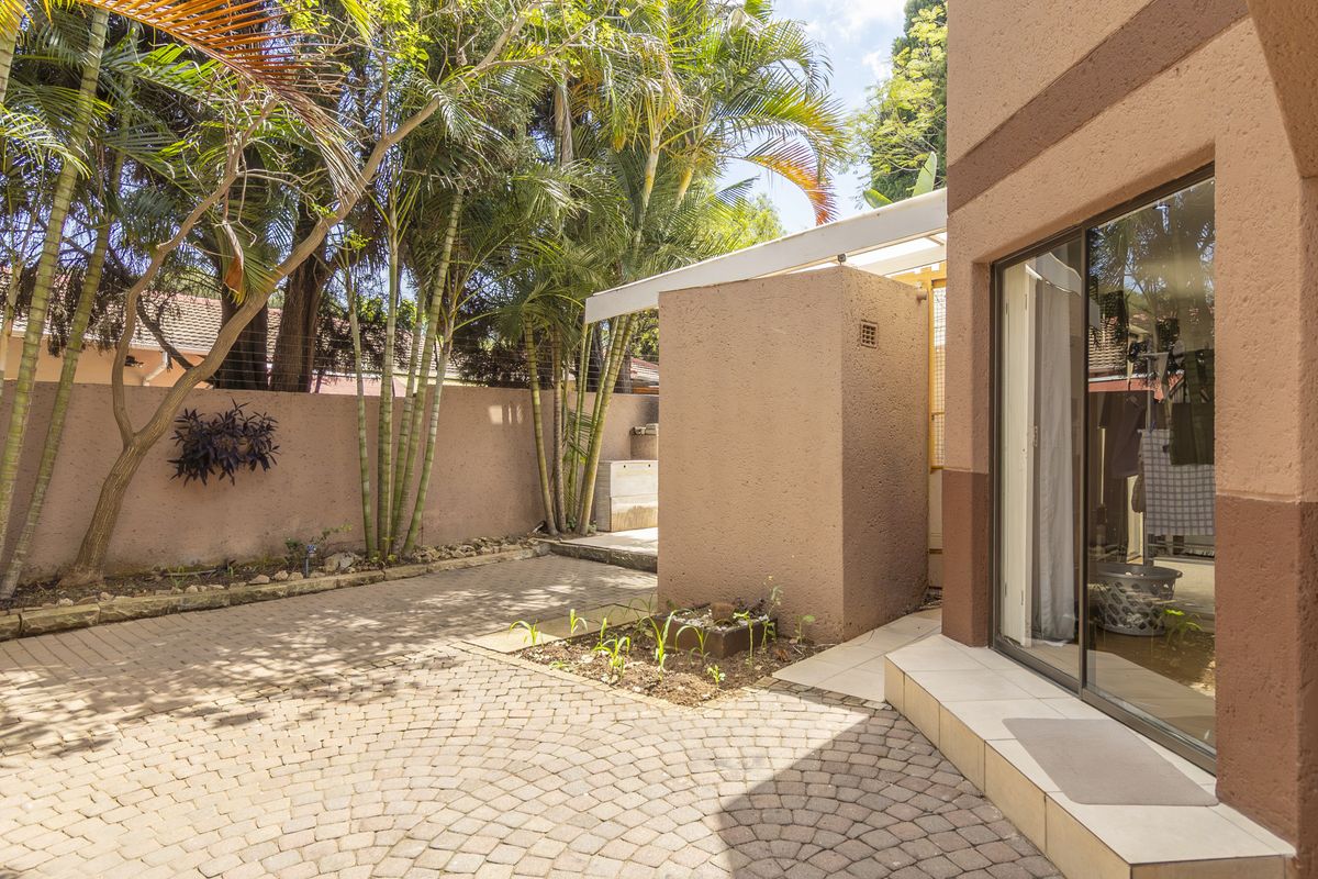 A private rear courtyard featuring paved flooring, a covered patio section, and direct access to the interior through a sliding glass door.