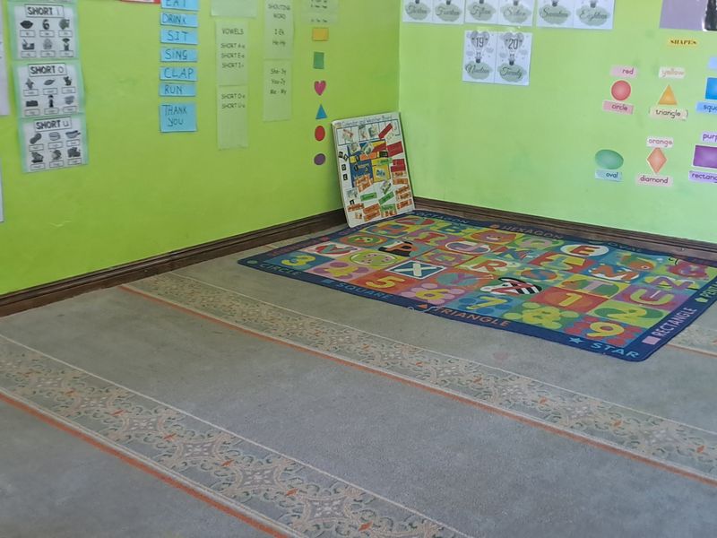 A room currently utilized as a learning space, featuring green painted walls and fitted carpeting, suitable for conversion into a bedroom or study.
