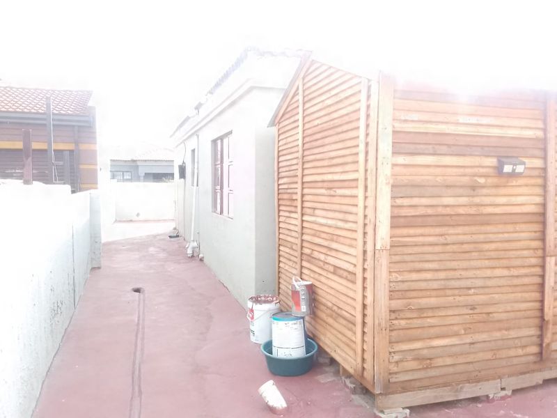 A side passage of the property featuring a timber shed, concrete paving, and boundary walling.