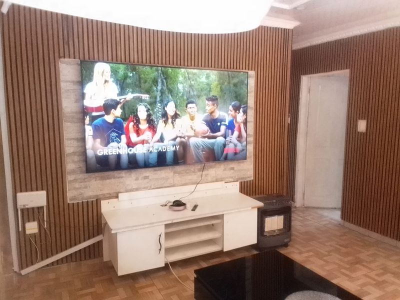 Living room featuring a modern slatted timber feature wall with stone veneer accent and parquet flooring.