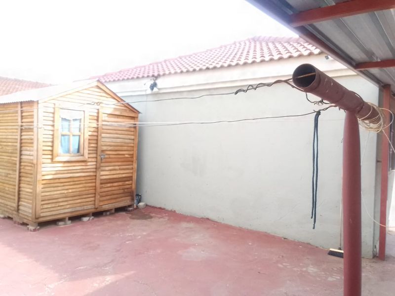 Rear exterior area featuring a wooden shed, a metal washing line pole, and a concrete patio surface.