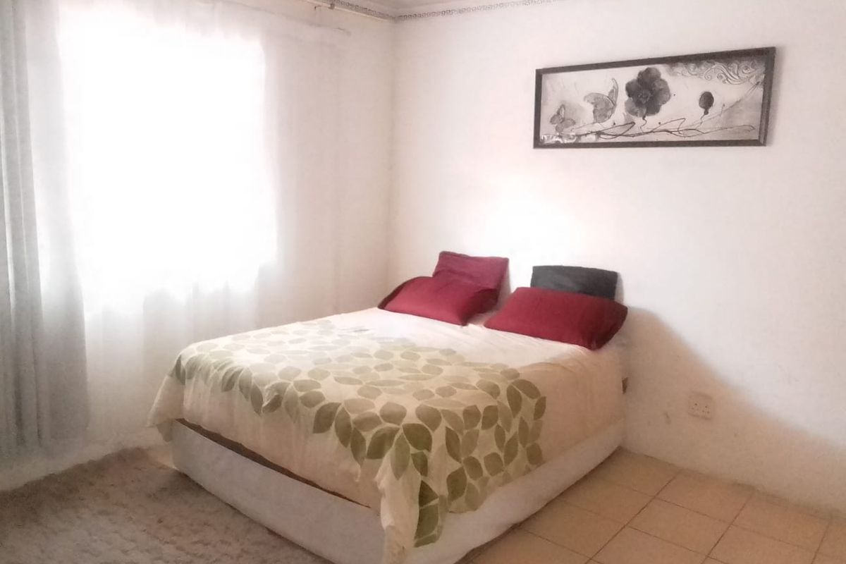 A simple bedroom featuring tiled flooring and decorative ceiling cornice, offering a functional space ready for personalization.