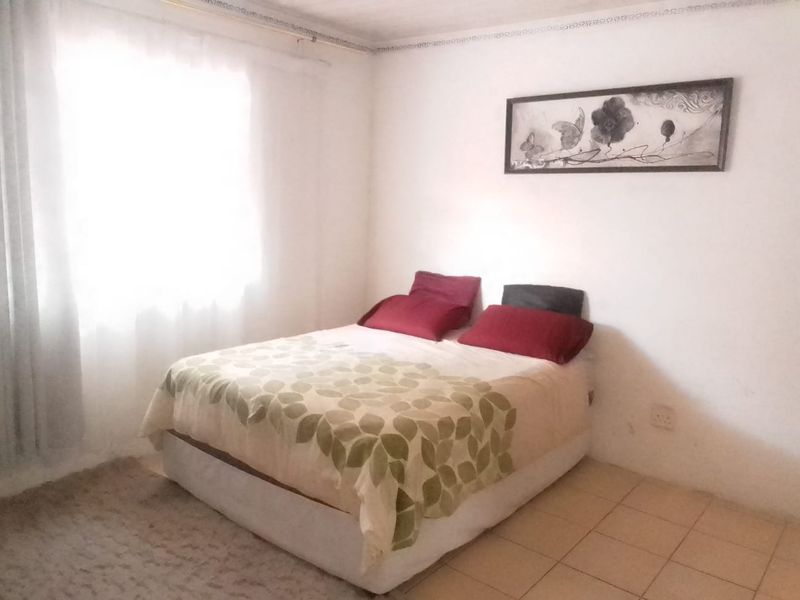 A simple bedroom featuring tiled flooring and decorative ceiling cornice, offering a functional space ready for personalization.
