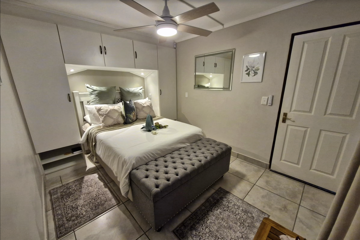 A well-maintained bedroom featuring built-in cabinetry, a ceiling fan, and neutral tiled flooring, offering a clean and functional living space.