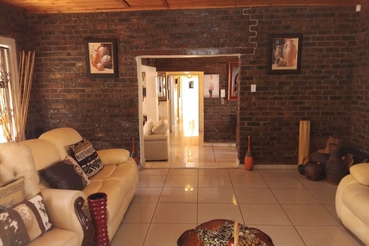 Spacious living area featuring exposed face-brick walls, timber-clad ceiling, and polished floor tiles, leading through to a central hallway.