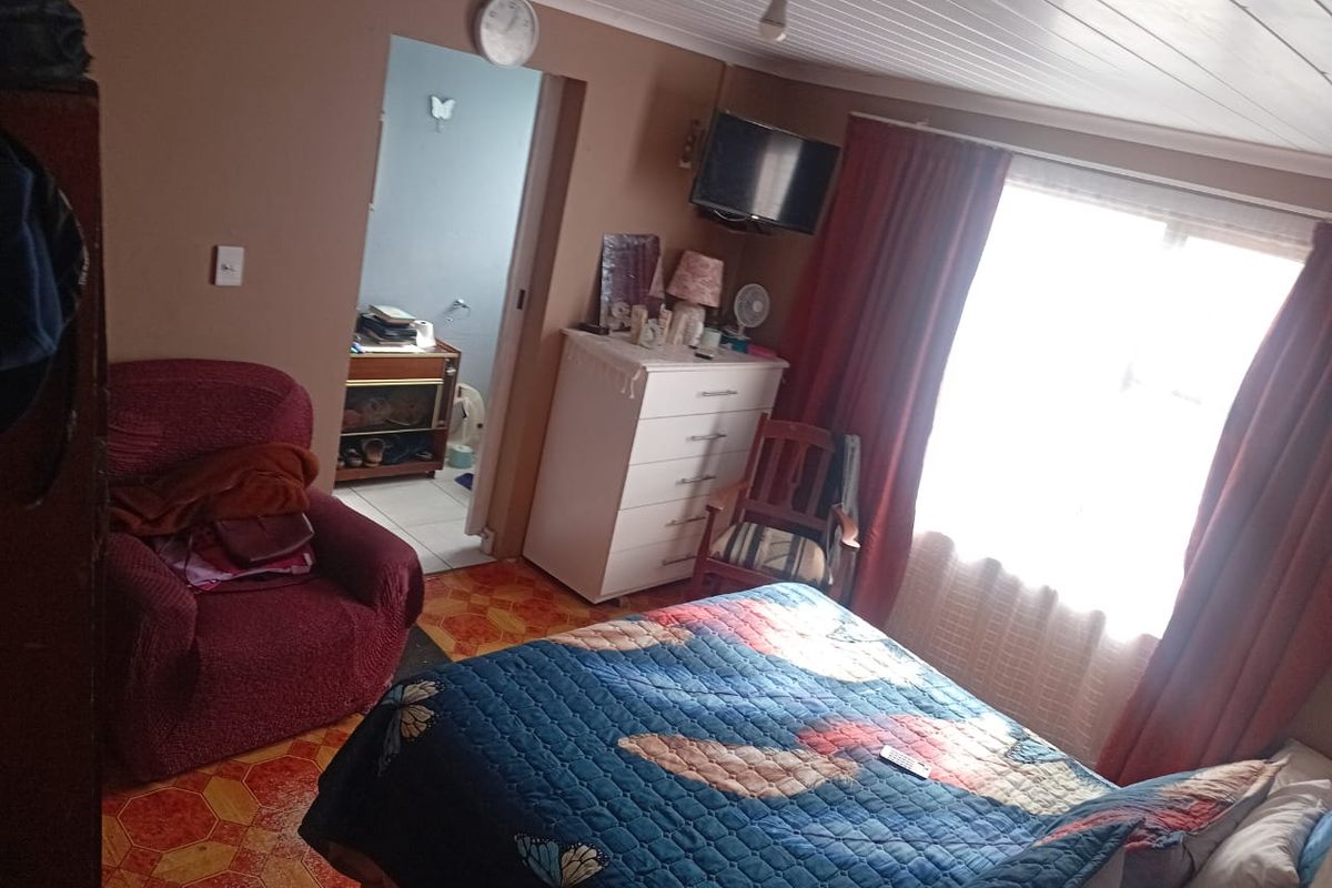 A bedroom featuring tongue and groove ceiling panels and tiled flooring, with an adjoining room visible through the doorway.