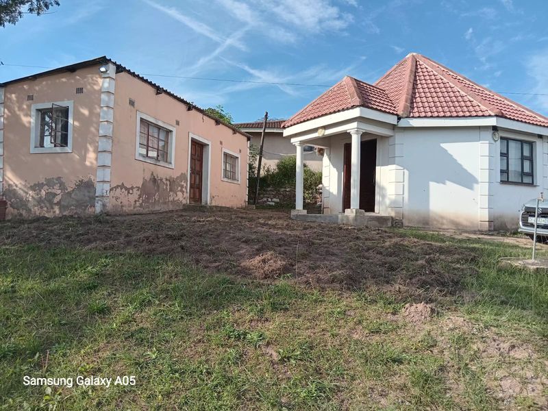 Exterior view of two residential structures featuring tiled roofs and masonry walls, showing significant signs of wear and maintenance requirements.