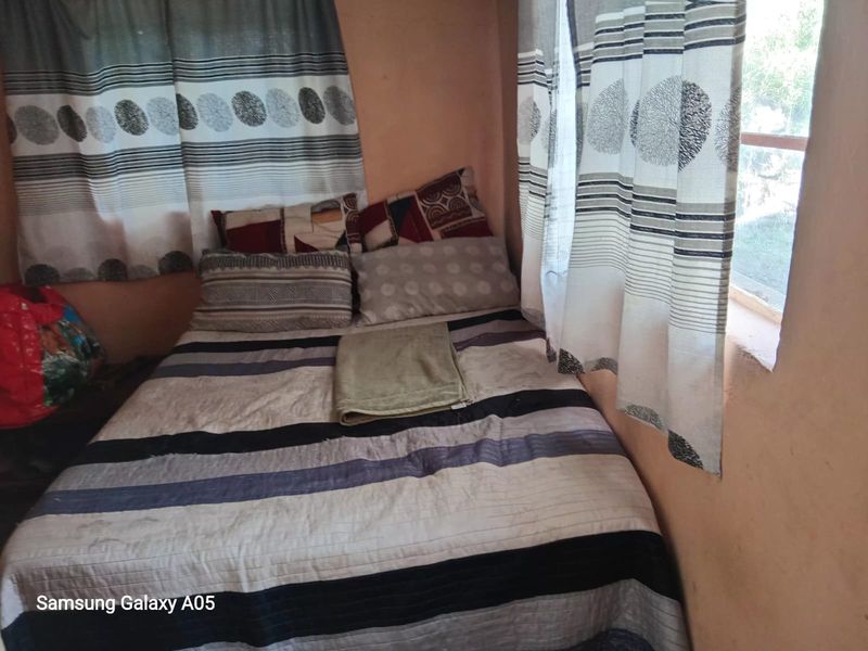 A compact bedroom featuring a window with curtains and basic wall finishes.