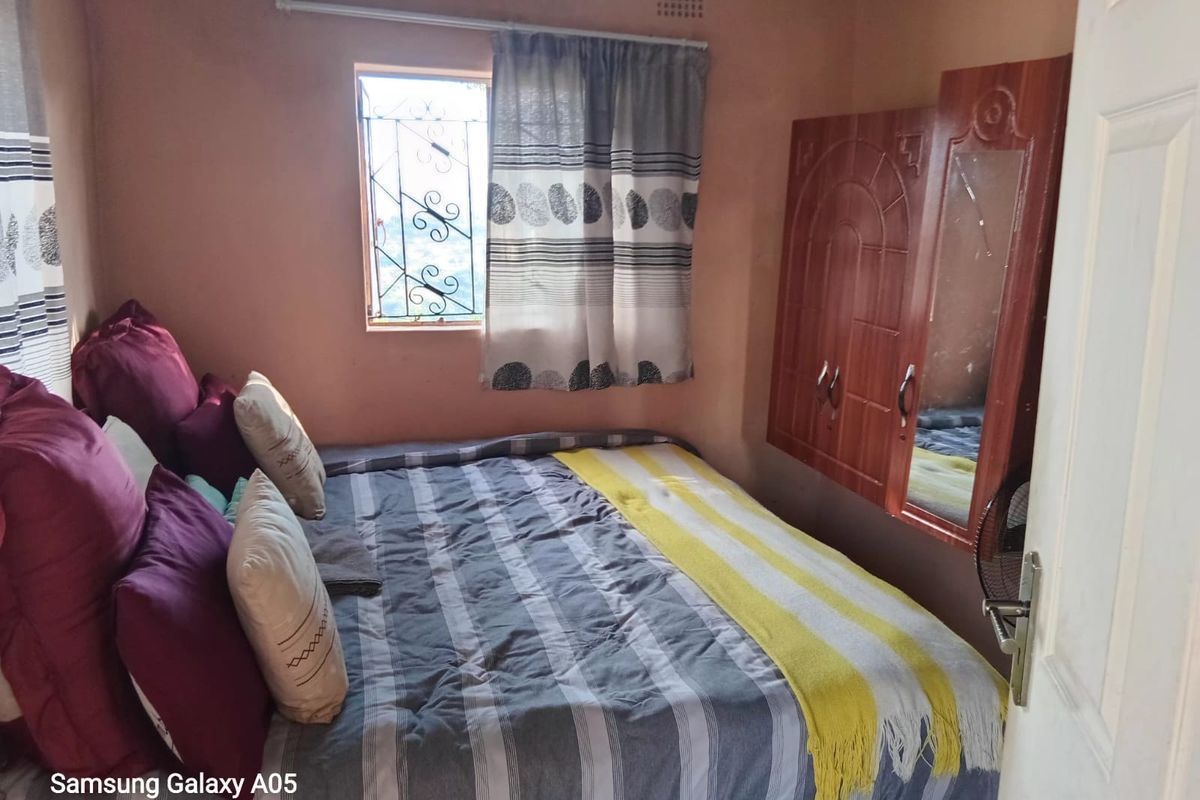 A compact bedroom featuring a built-in wardrobe and a window with security bars, requiring cosmetic updates to improve the overall finish.