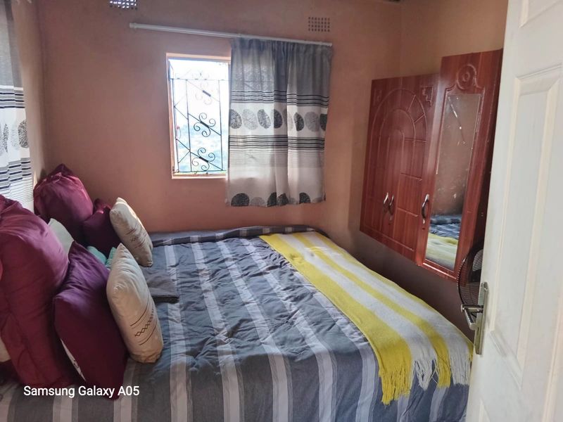 A compact bedroom featuring a built-in wardrobe and a window with security bars, requiring cosmetic updates to improve the overall finish.