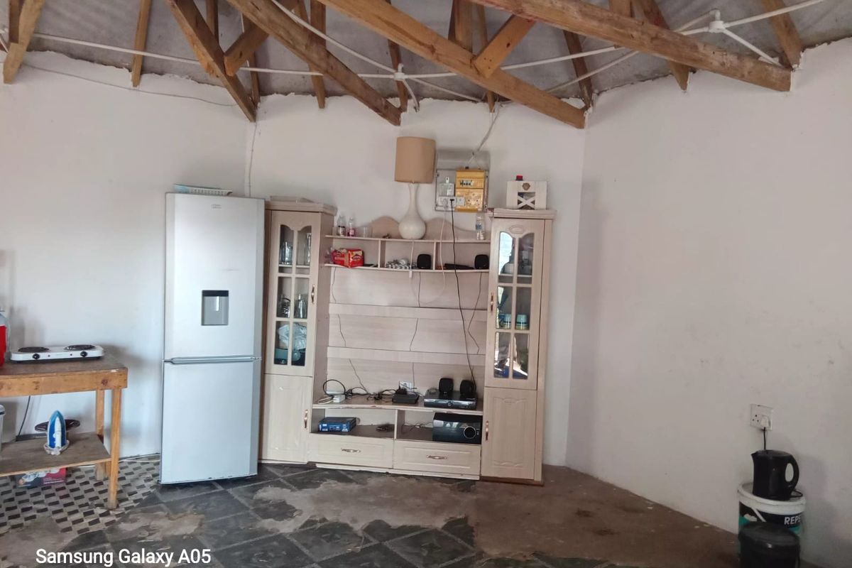 Living area featuring exposed timber roof trusses and tiled flooring, requiring cosmetic updates and finishing to improve the overall aesthetic and condition.