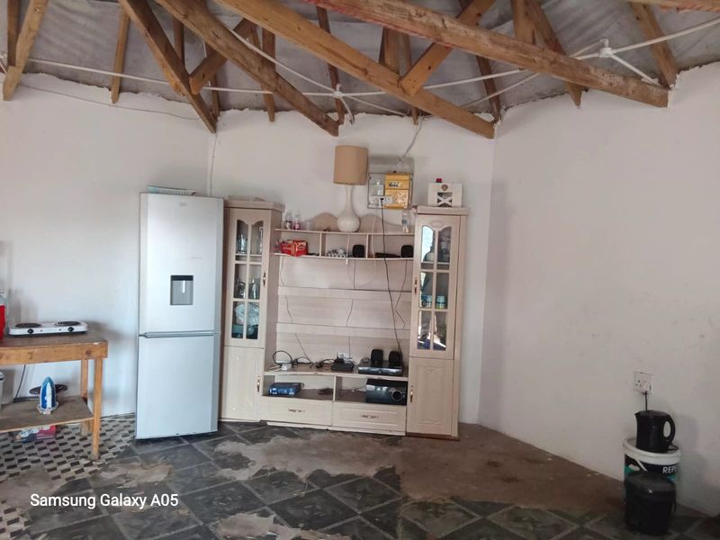Living area featuring exposed timber roof trusses and tiled flooring, requiring cosmetic updates and finishing to improve the overall aesthetic and condition.