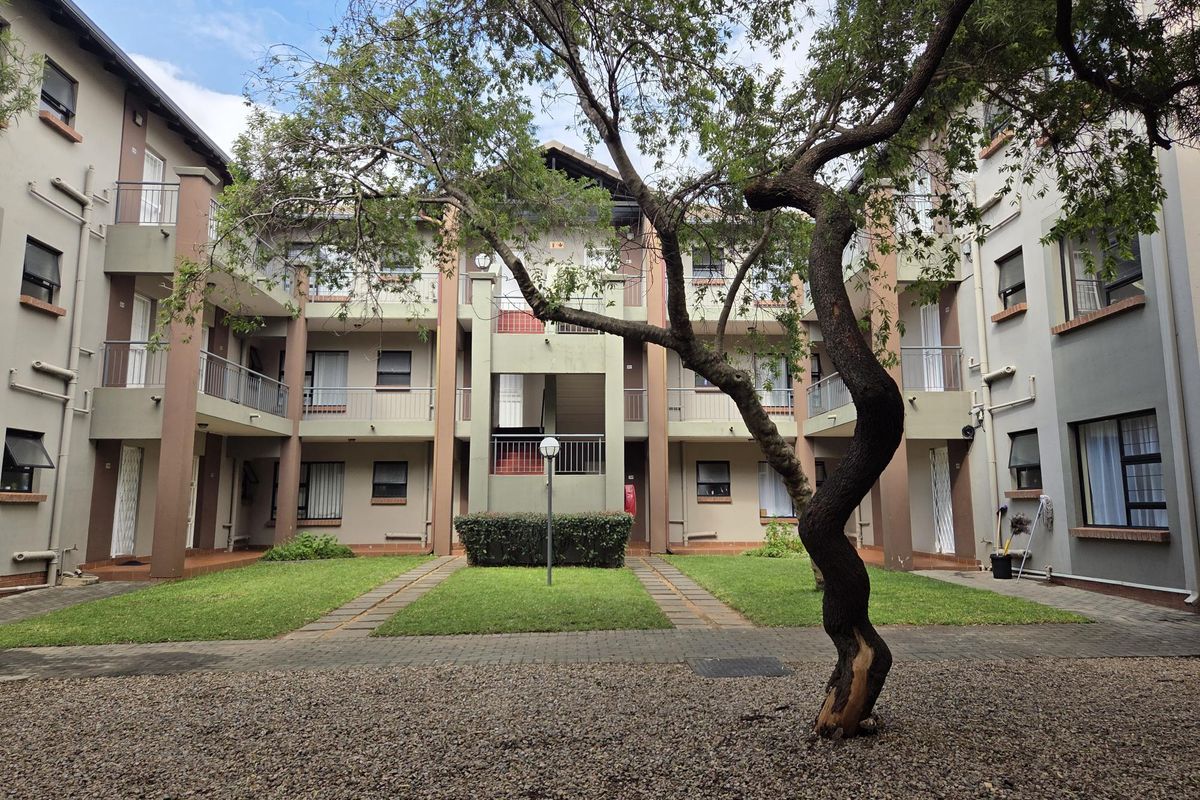 A view of the apartment complex courtyard featuring paved walkways, manicured lawns, and multi-level balconies with security gates.