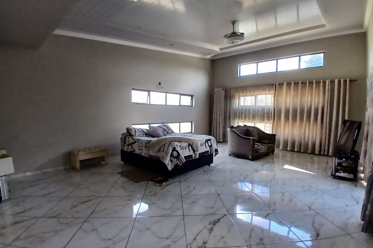 Spacious bedroom featuring high ceilings with a fan, large windows for natural light, and polished marble-look floor tiles.