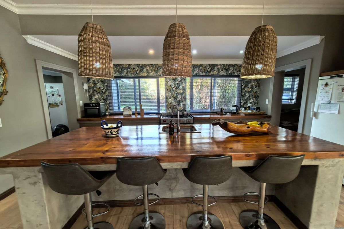 A well-appointed kitchen featuring a large wooden island with a concrete base, integrated sink, and gas cooktop, complemented by stylish pendant lighting.