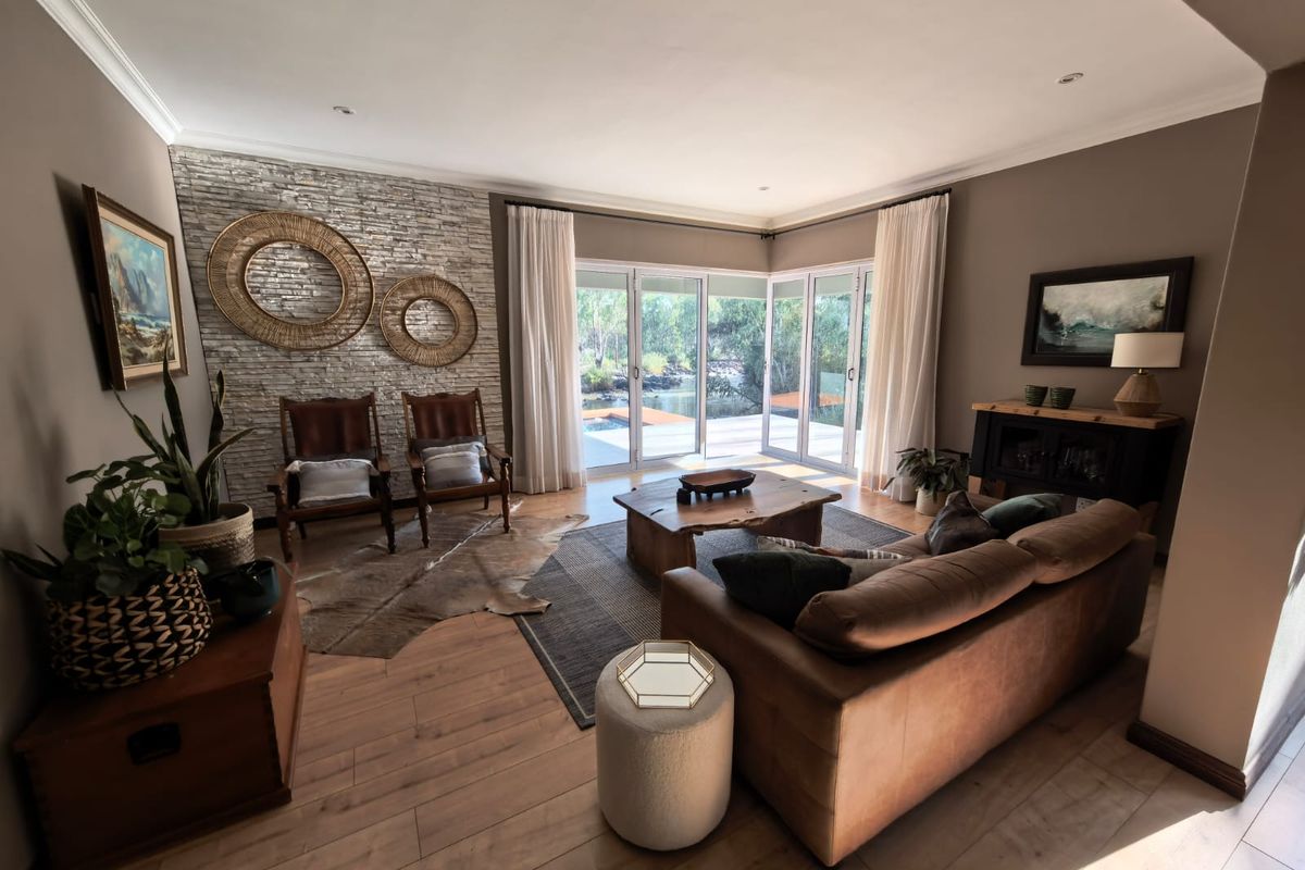 A well-maintained living room featuring a stone accent wall, laminate flooring, and large sliding glass doors that provide natural light and garden access.