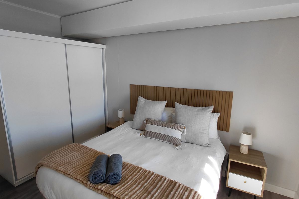 A well-maintained bedroom featuring a modern slatted wood headboard and a large built-in wardrobe with sliding doors.