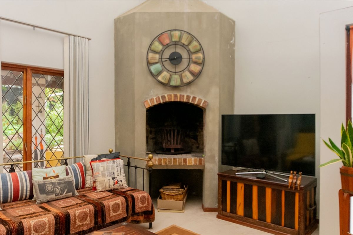 A cozy living room featuring a prominent built-in masonry fireplace with brick detailing and large windows providing natural light.